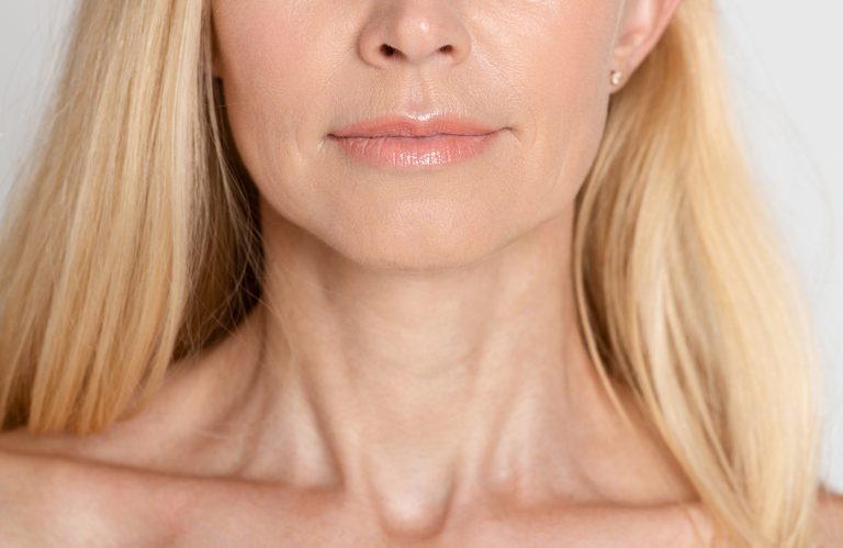 Beautiful mature woman with wrinkled neck, grey background