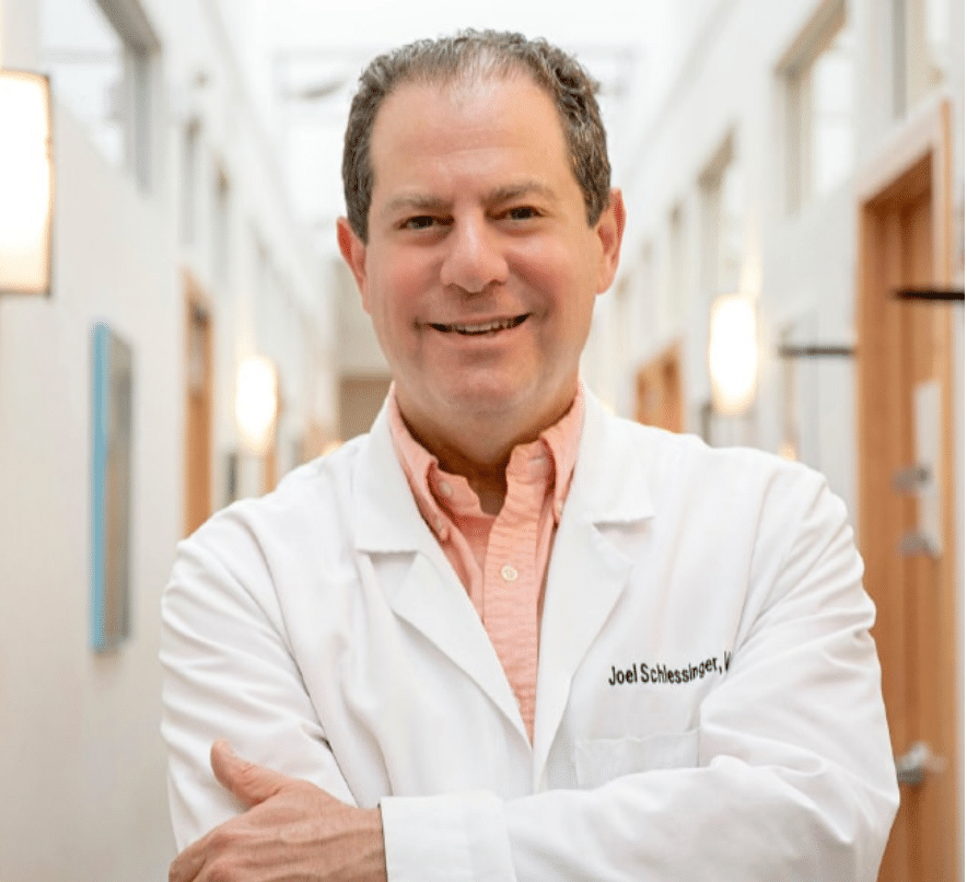 Profile of Dr. Joel Schlessinger in lab coat standing in a hallway inside Schlessinger MD office