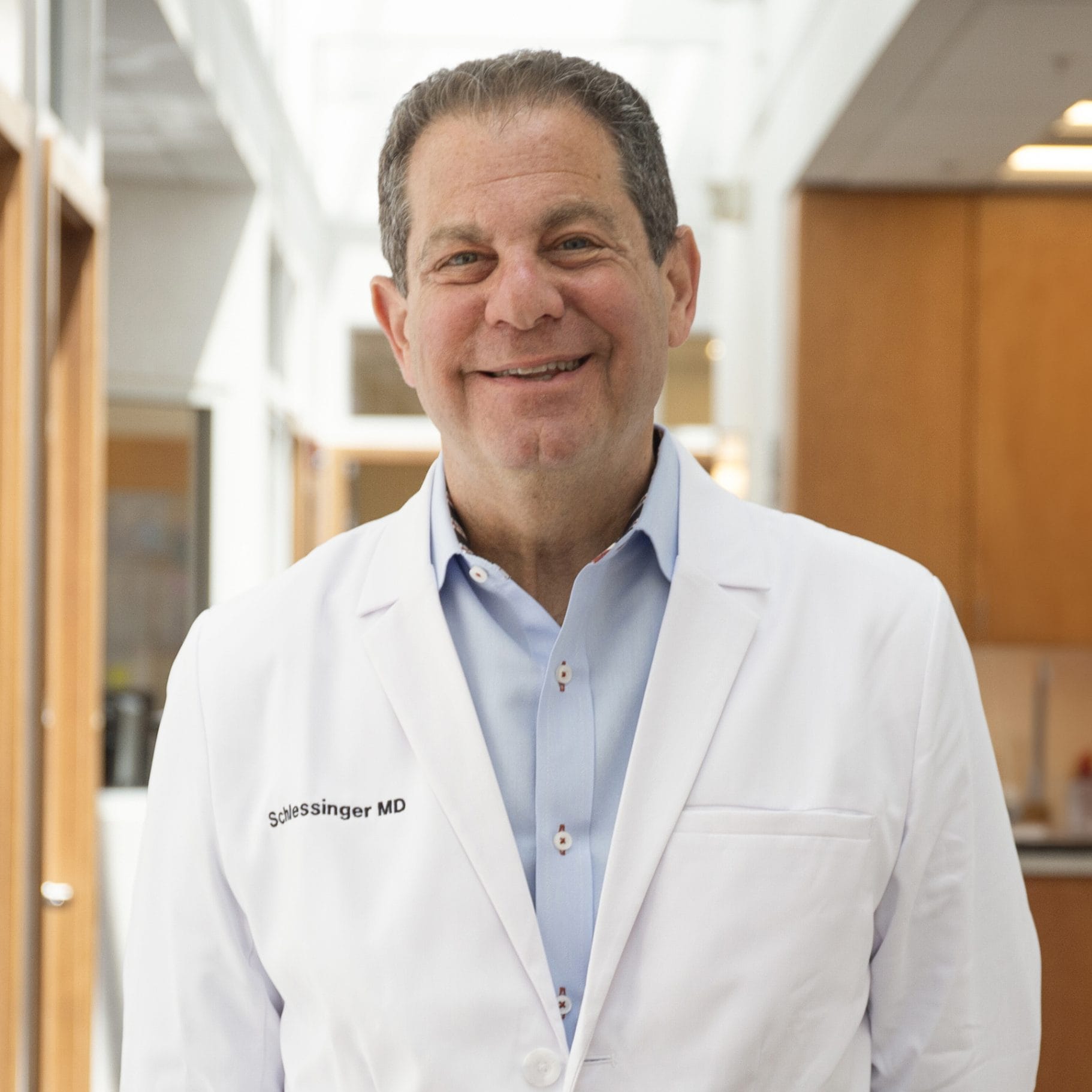 Profile of Dr. Joel Schlessinger in lab coat standing in a hallway inside Schlessinger MD office
